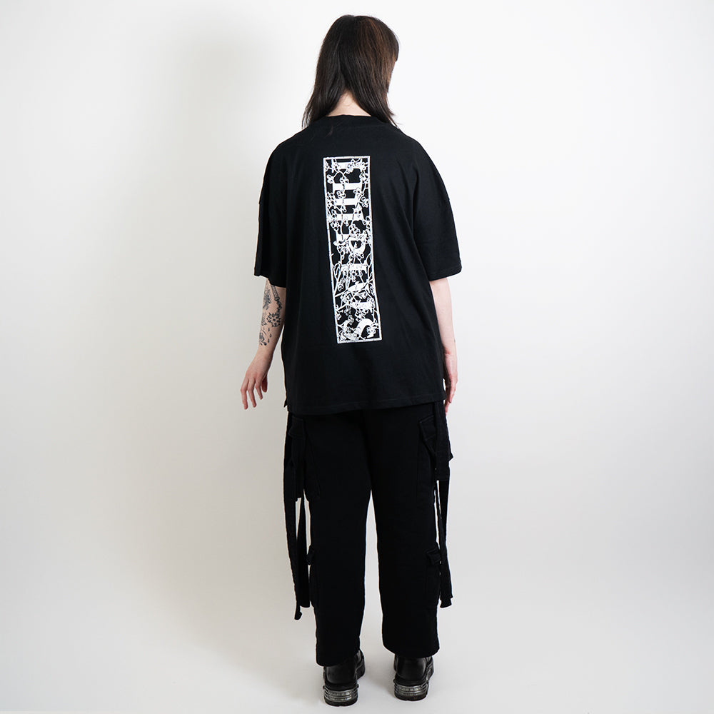 A full body shot of an alternative model wearing a black oversized tee with the impius cherry blossom back design