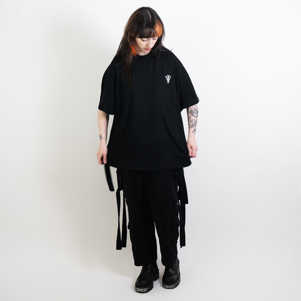 A full body image of an alternative model wearing a black oversized tee with the impius logo