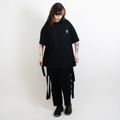 A full body image of an alternative model wearing a black oversized tee with the impius logo