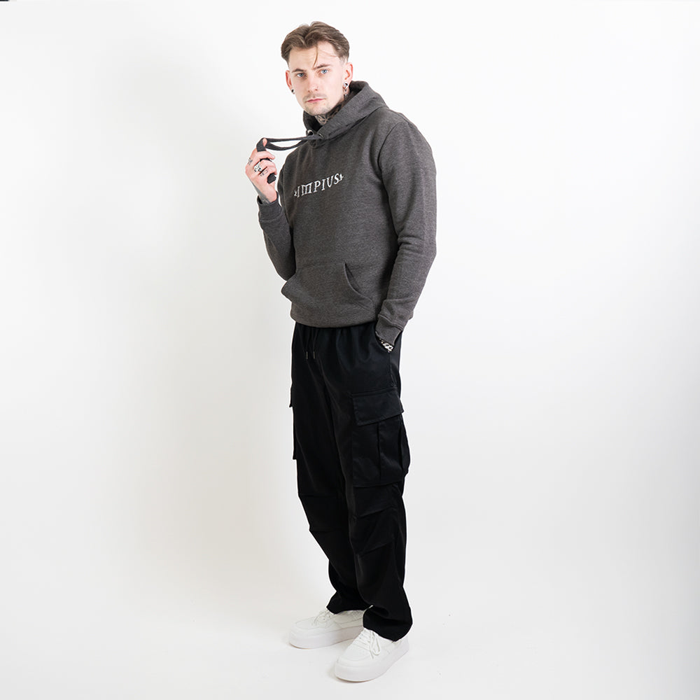 A full body image of a tattooed model wearing a grey hoodie with the Impius logo