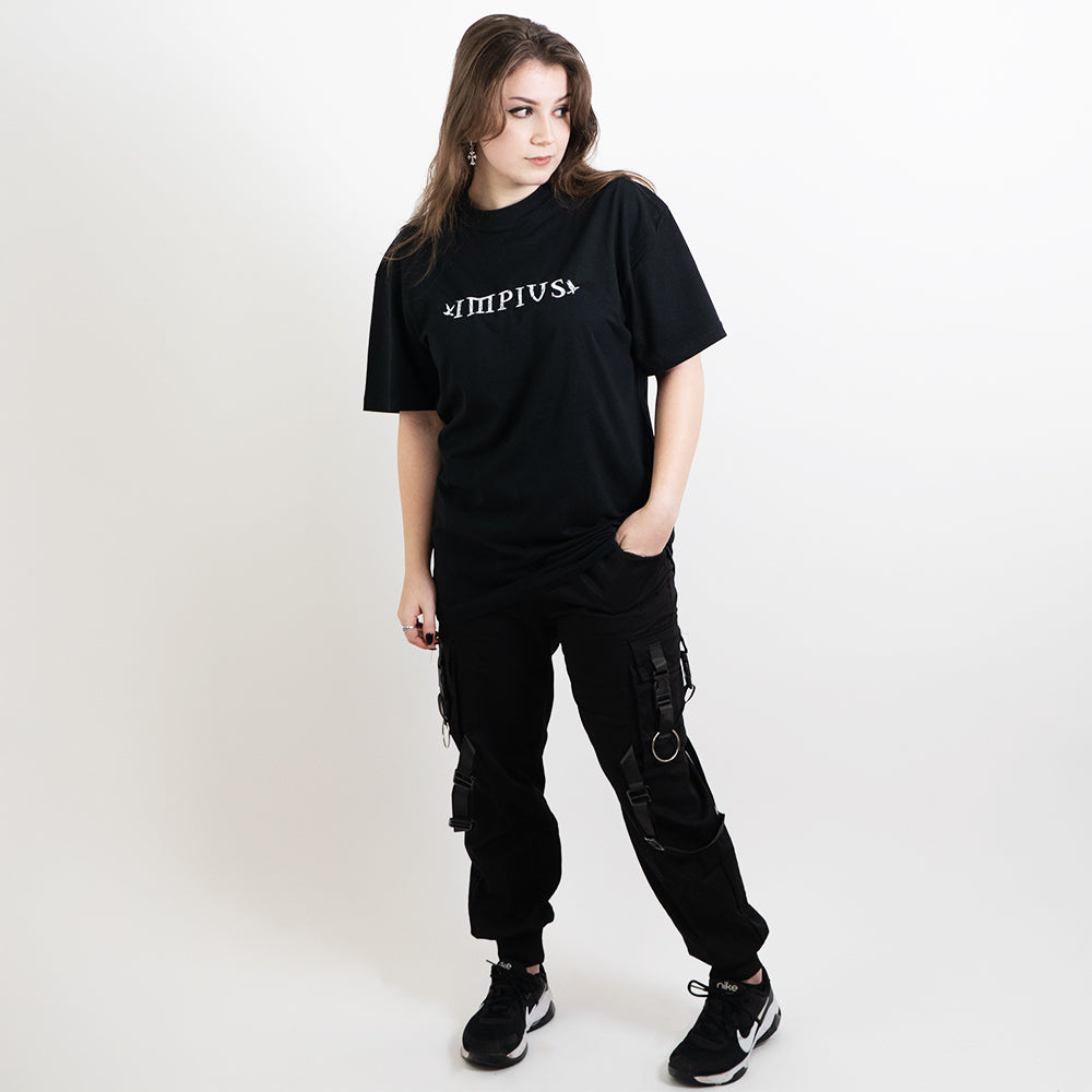 A full body image of an alternative model wearing a black oversized tee with the impius logo