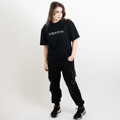 A full body image of an alternative model wearing a black oversized tee with the impius logo
