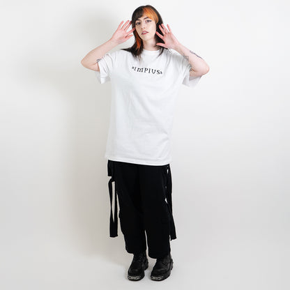 A full body image of an alternative model wearing a white oversized tee with the impius logo