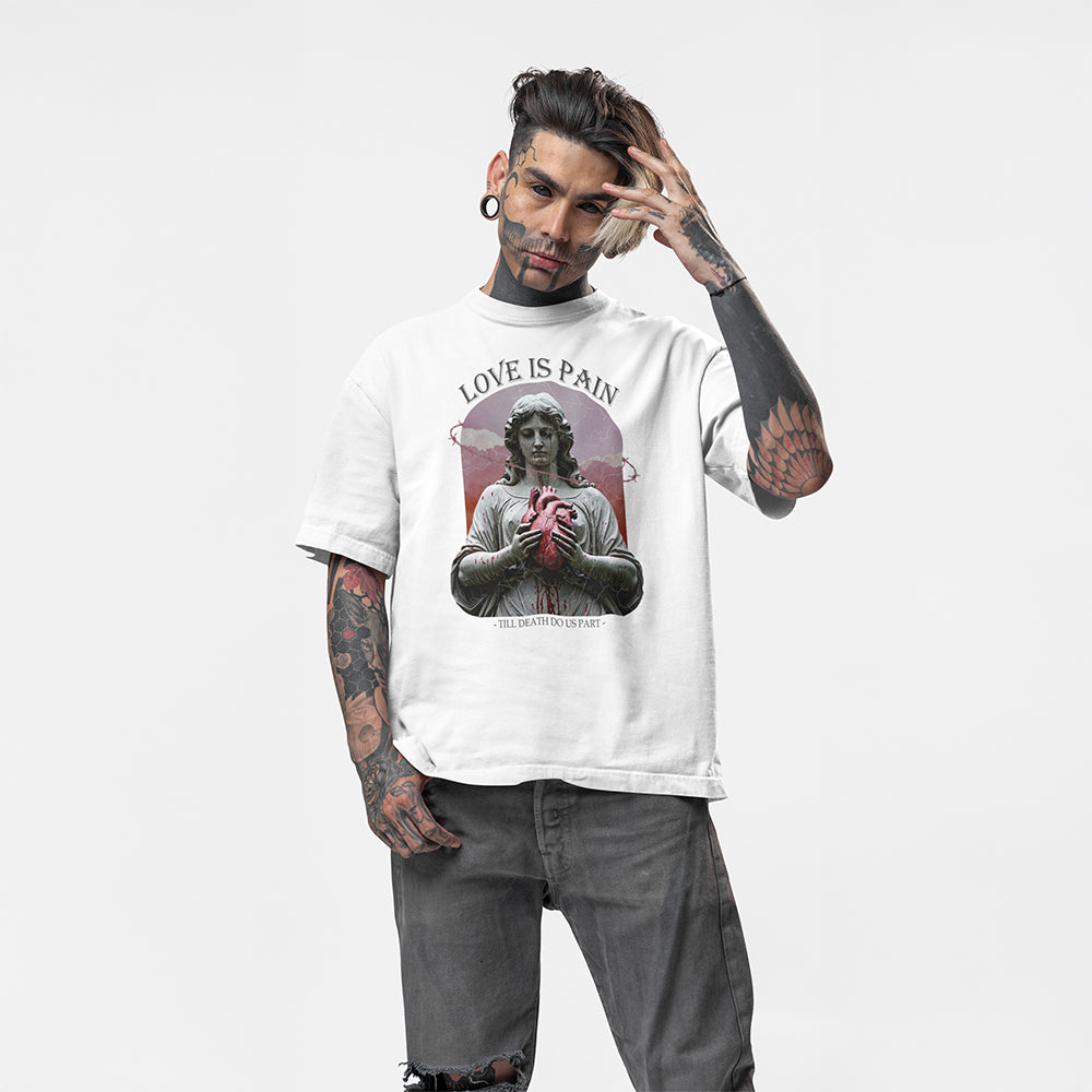A full body image of a tattooed model wearing a white oversized tee with the impius love is pain design